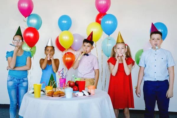 Children on a birthday celebration with balls, caps, sweets and laughs.