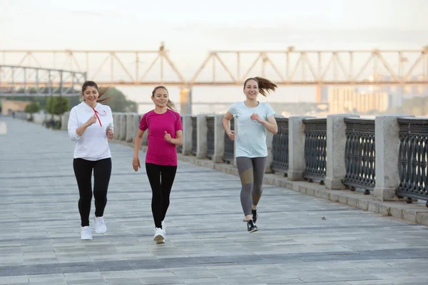 有三个身穿运动服的女人在河边公园里跑步 — 图库照片