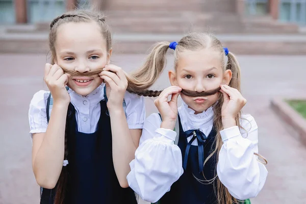 Zwei Schulmädchen Uniform Amüsieren Sich Machen Schnurrbärte Aus Zöpfen — Stockfoto