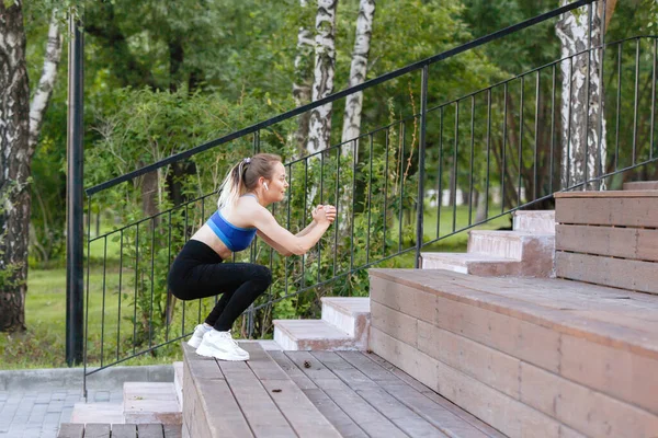 穿着运动服的女人会蹲在城市公园楼梯的木板台阶上 — 图库照片