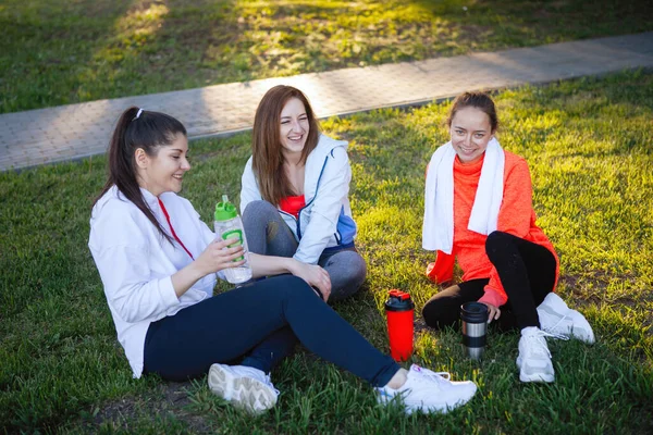 Trzy Kobiety Odzieży Sportowej Odpoczywają Latem Zielonym Trawniku Parku Miejskim — Zdjęcie stockowe
