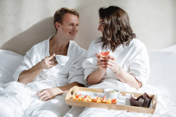 男人和女人在床上吃早餐和一盘食物 在酒店房间里快乐的一对 — 图库照片