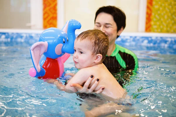 Woman child trainer and toddler swim and study in blue water pool