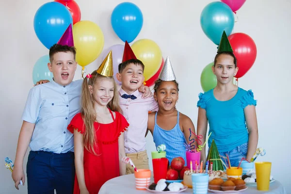 Children on a birthday celebration with balls, caps, sweets and laughs.