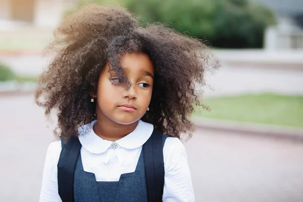 Portrait of a sad african american girl on a sunny summer day outdoors.