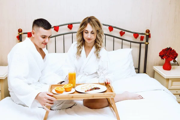 情人男女在床上吃饭 在一盘咖啡 可爱的夫妻 白色浴衣 情人节 — 图库照片