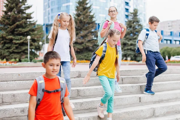 バックパック付きのカラフルな服の子供たちは学校までの階段を歩いています — ストック写真