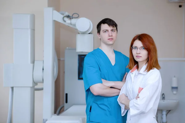 医務室のX線装置の近くに男性医師と看護師の放射線技師が立っている — ストック写真