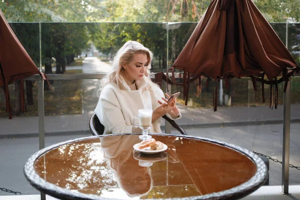 Πορτρέτο Μιας Ξανθιάς Κυρίας Ένα Τραπέζι Ένα Καφέ Ένα Smartphone — Φωτογραφία Αρχείου