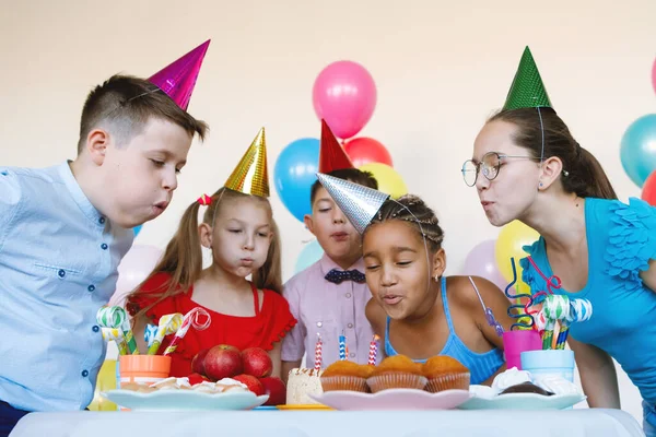 在生日庆祝活动上 戴帽子的孩子们吹灭了蛋糕上的蜡烛 假日概念 — 图库照片