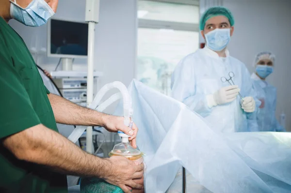 Anesthesiologist puts on a mask for inhalation anesthesia to a patient before surgery.