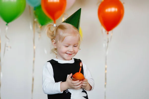 キャップの女の子はケーキの上に誕生日のろうそくを吹きます — ストック写真