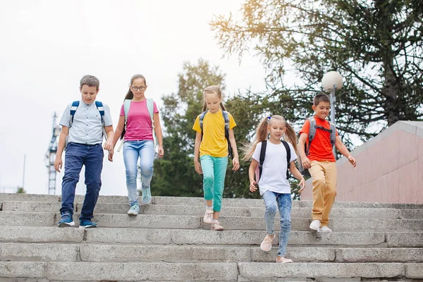 バックパック付きのカラフルな服の子供たちは学校までの階段を歩いています — ストック写真