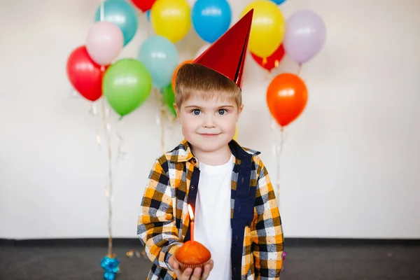 キャップの少年はケーキの上に誕生日のろうそくを吹き消す — ストック写真