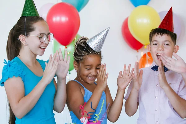 Children on a birthday celebration with balls, caps, sweets and laughs.