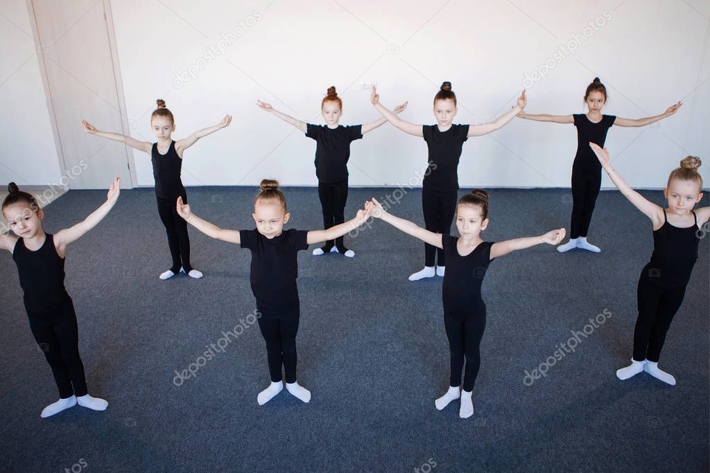 Group of teenage girls in dance, ballet, rhythmic gymnastics classes. Black leotards, hair in a bun, choreography, attentiveness, white socks.