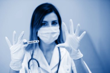 Bir hemşirenin elinde koronavirüs testi yapılmış bir test tüpü ve lateks eldivenler. Seçili Odaklanma.