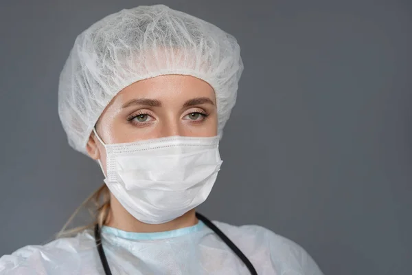 Doctor with a stethoscope, in a protective mask and cap, silicone gloves.