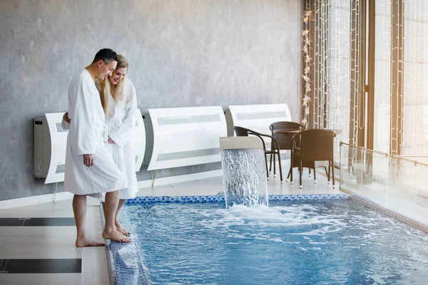 两个人站在温泉池边 一个男人和一个女人穿着白色浴衣 抱着蓝水边 — 图库照片