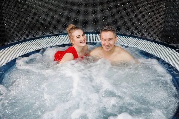 Una Pareja Joven Bonita Está Relajando Jacuzzi Agua Azul Espumosa — Foto de Stock