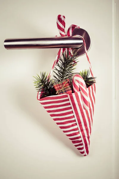 Petit sac de Noël avec branche et canne à bonbons suspendue sur la poignée de la porte — Photo