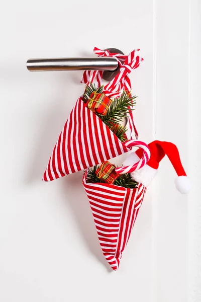 Small Christmas bag with branch and candy cane hanging on door handle — Stock Photo, Image