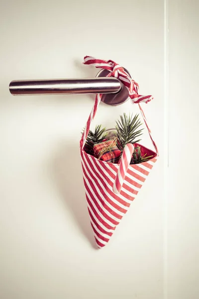 Saco de Natal pequeno com ramo e cana-de-açúcar pendurado na maçaneta da porta — Fotografia de Stock