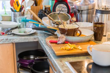 Kirli bulaşık yığınıyla dolu dağınık bir mutfak. Zorunlu İstifçilik Sendromu 