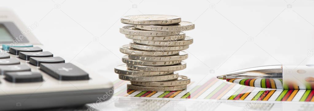 stacked euro coins and calculator laying on financial business chart