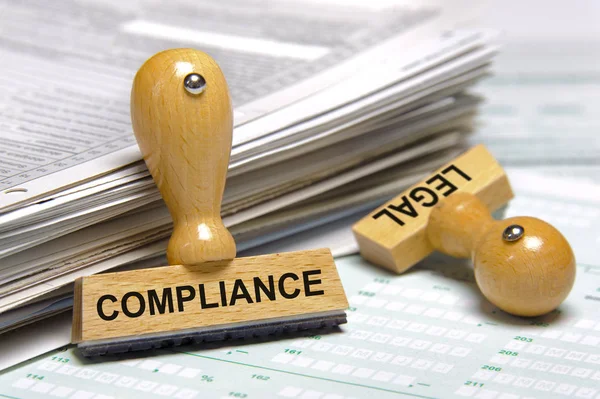 Compliance and legal printed on stamps laying on stack of forms — Stock Photo, Image