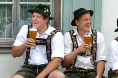 In many villages of Bavaria it is historical customs to erect an decorated high tree at 1. May by local men, but two local men are resting and drinking beer clipart