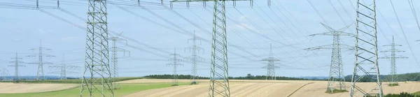 Many high-voltage pylons for transporting electricity from a pow — Stock Photo, Image