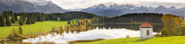 アルプスの山々の前に草原や湖が広がるパノラマ風景 — ストック写真