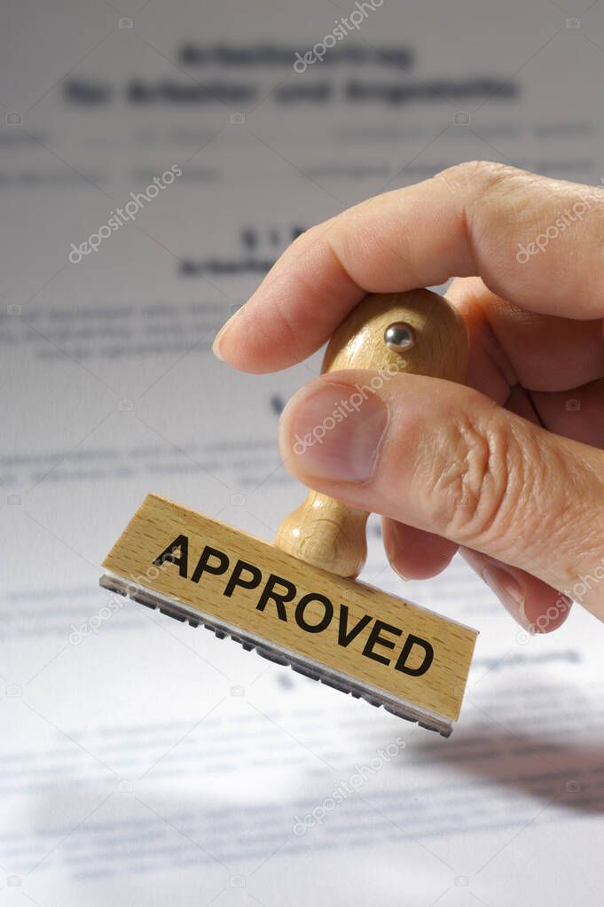 approved printed on rubber stamp in hand