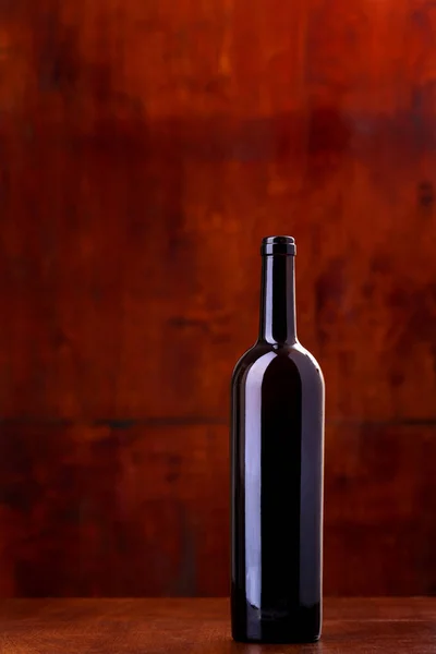 Láhev vína na tmavě červeném pozadí — Stock fotografie