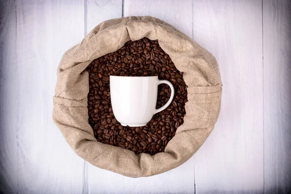 Tazza di caffè in un sacchetto pieno di chicchi di caffè — Foto Stock