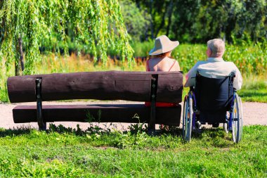 tekerlekli sandalye ve genç kadın bir bankta yaşlı adam