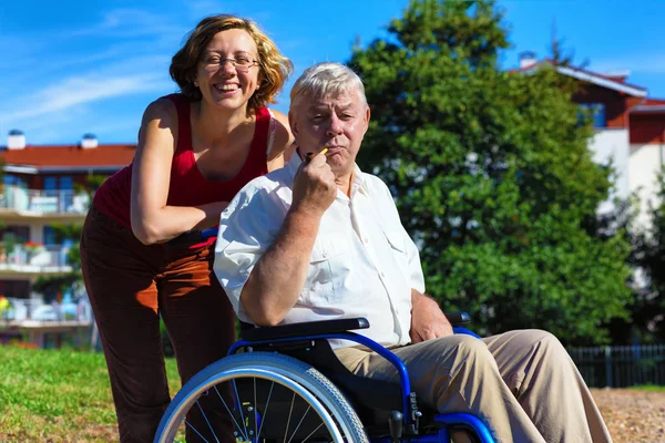 Man on wheelchair with smiling young woman — Stock Photo, Image
