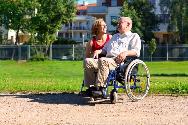 Άντρας στο αναπηρικό καροτσάκι με νεαρή γυναίκα — Φωτογραφία Αρχείου