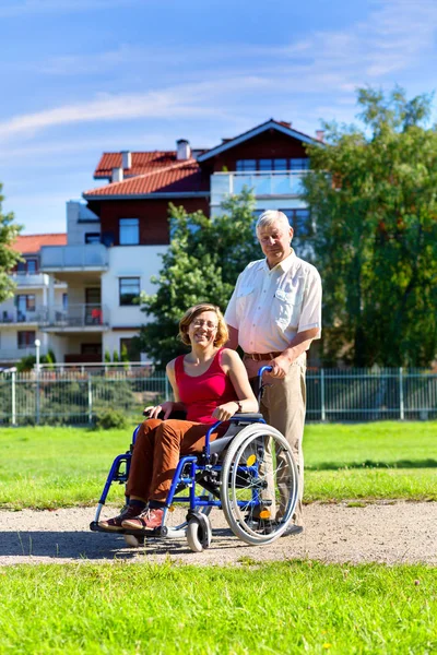 Woman on wheelchair and older man — Stock Photo, Image