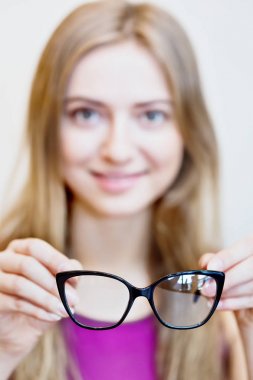 black eyeglasses in hands of a blonde woman clipart
