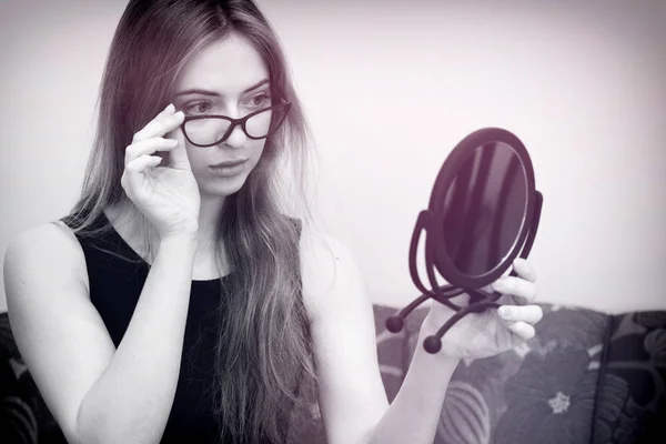 Жінка в окулярах дивиться у дзеркало — стокове фото
