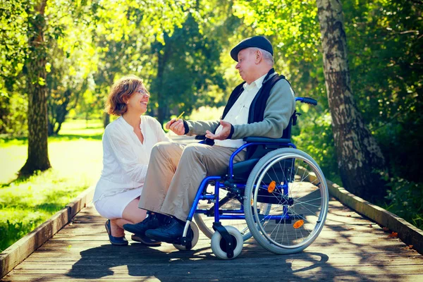 Old man on wheelchair and young woman in the park Royalty Free Stock Images