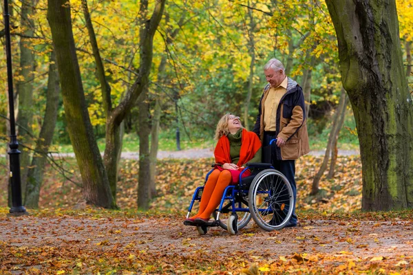 Woman on wheelchair and older man in the park — Stock Photo, Image