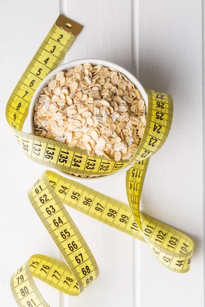 Conceito de dieta. Farinha de aveia e fita métrica . — Fotografia de Stock