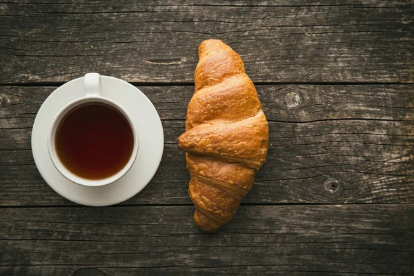 Sabroso croissant mantecoso y taza de té . — Foto de Stock