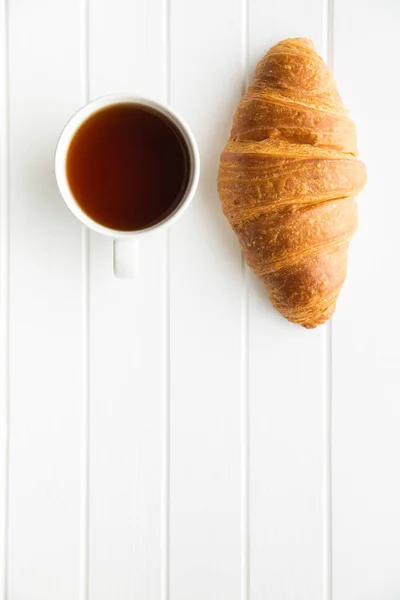 Croissant amanteigado saboroso e xícara de chá . — Fotografia de Stock