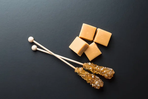 Braune Zuckerkristalle auf Stick und Karamellbonbons. — Stockfoto