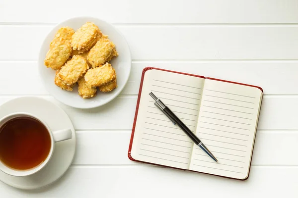 Blocco note vuoto con penna e biscotti con tè . — Foto Stock