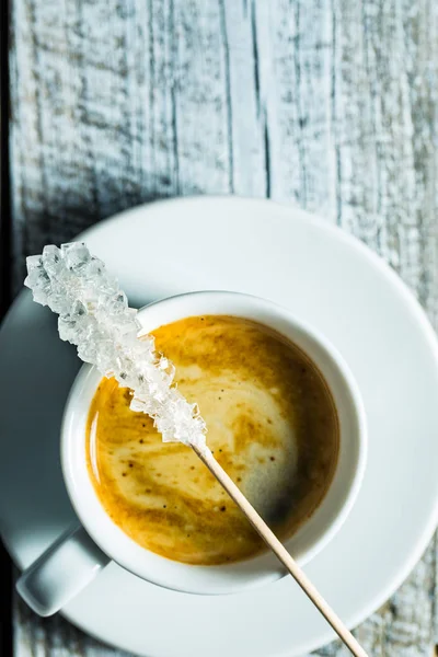 Кристаллизованный сахар на деревянной палочке и чашке кофе . — стоковое фото